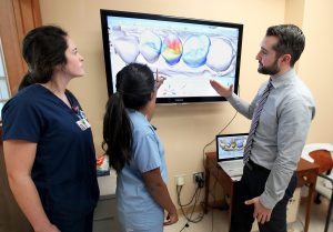 Students of the College of Dental Medicine review an image on a monitor. 