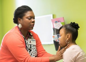 A physician examines a child's throat in office. 