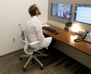 An MUSC clinical expert speaks to a patient through a computer and camera for telehealth.