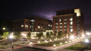 A nighttime view of the Clyburn building, with lights across the park and illuminating the building. 