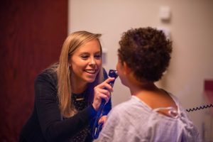A College of Nursing student examines a young child's mouth.