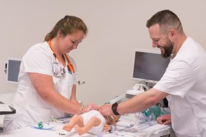 Two students of the College of Nursing work together using a mannequin modeled after an infant in a simulation lab. 